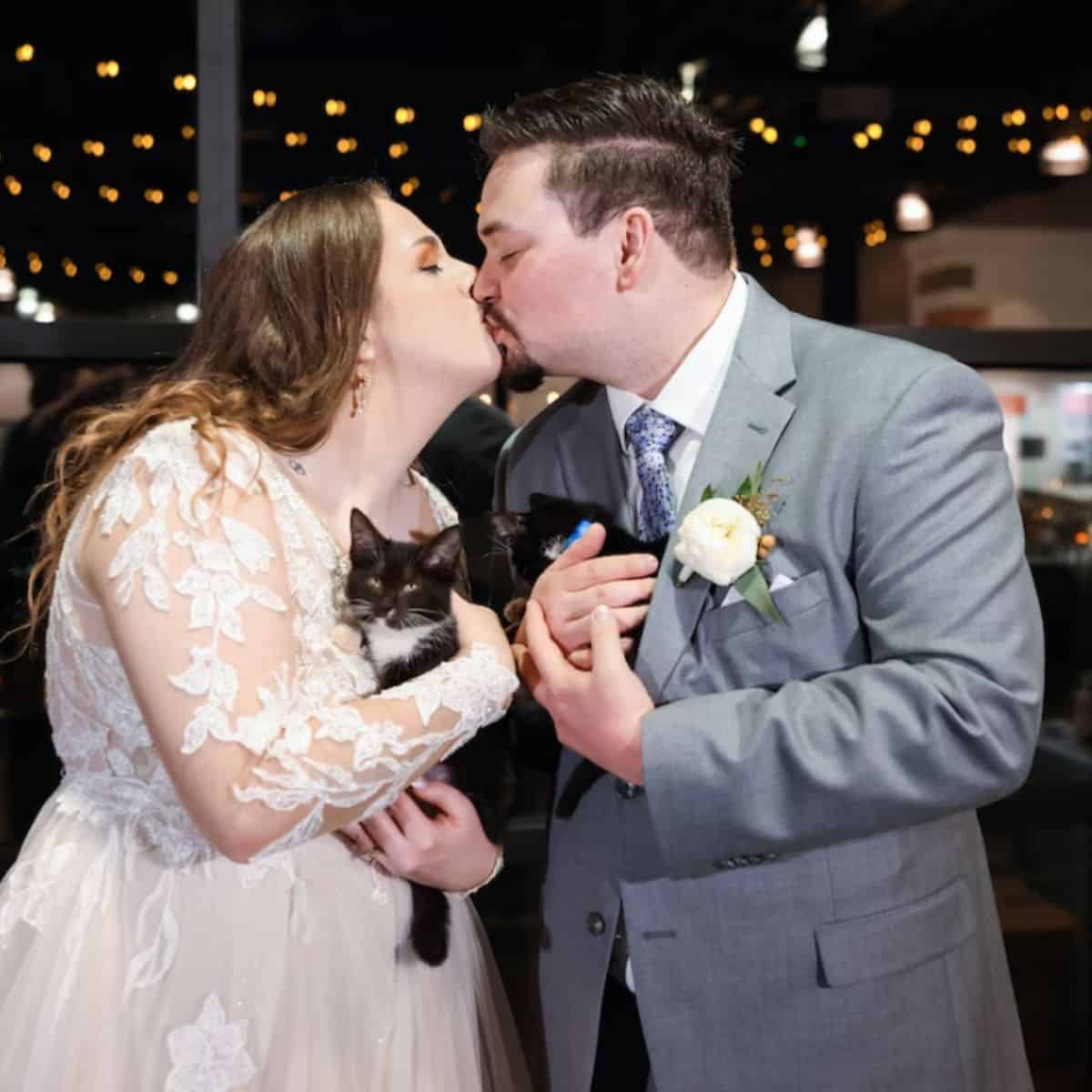 couple kissing and holding a cats