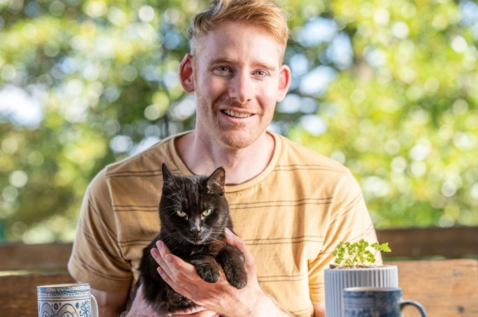 man-hugging-his-black-cat