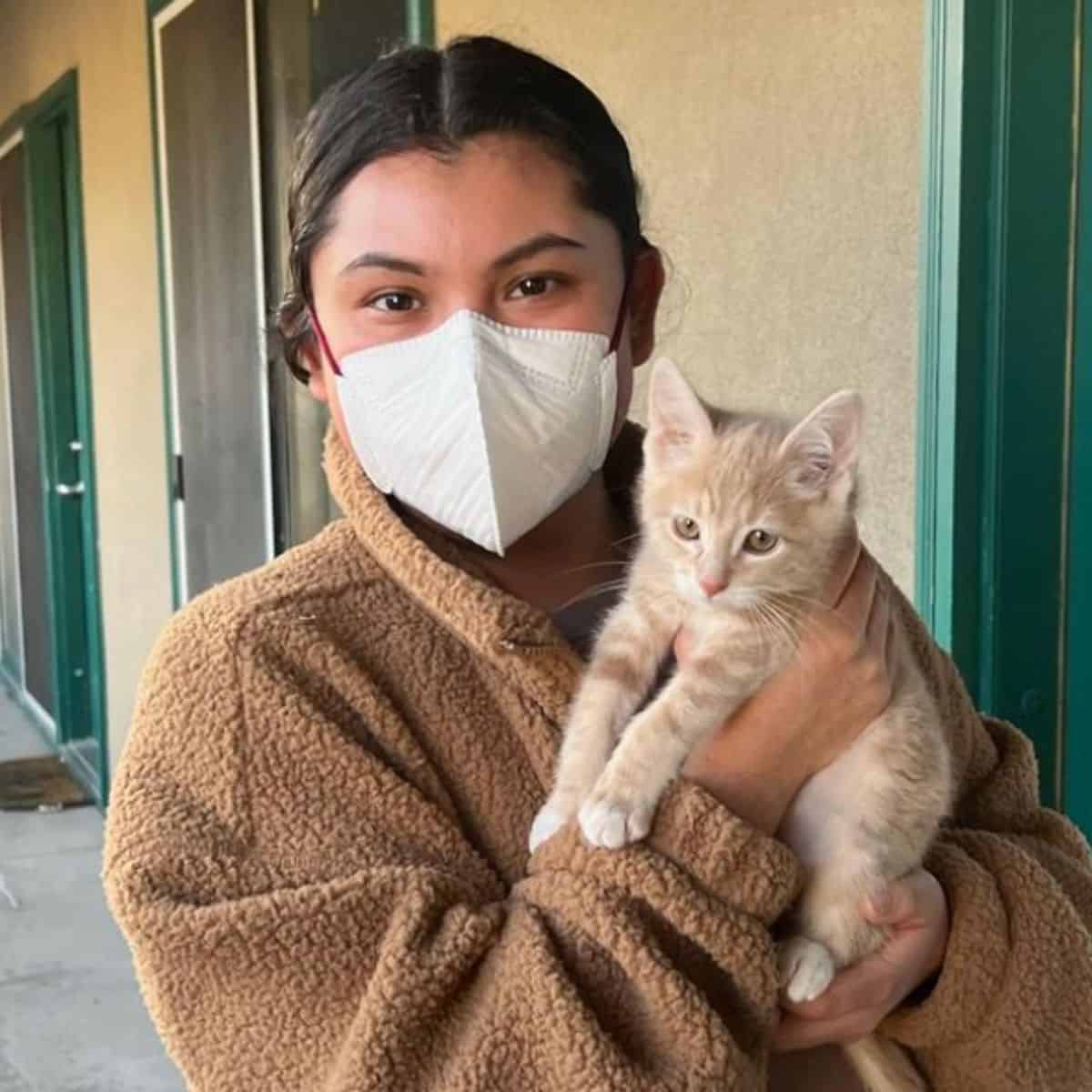 woman with black hair holding a cute little kitten