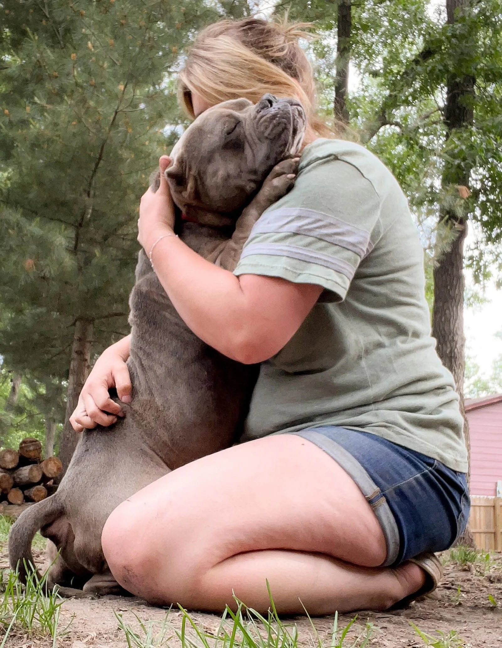 woman and dog hugging each other in the garden